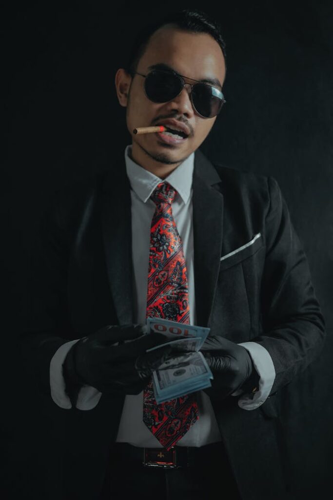 Stylish man in sunglasses counting cash with a cigarette.